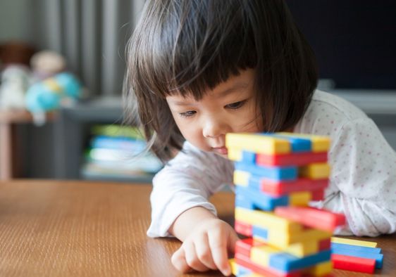 Little preschooler playing with wooden blocks.