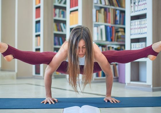 Young woman reading and practicing yoga in the library.