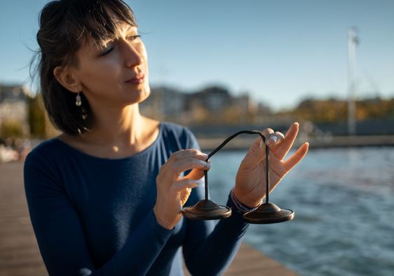 Woman holding a tingsha bell instrument for vibration.