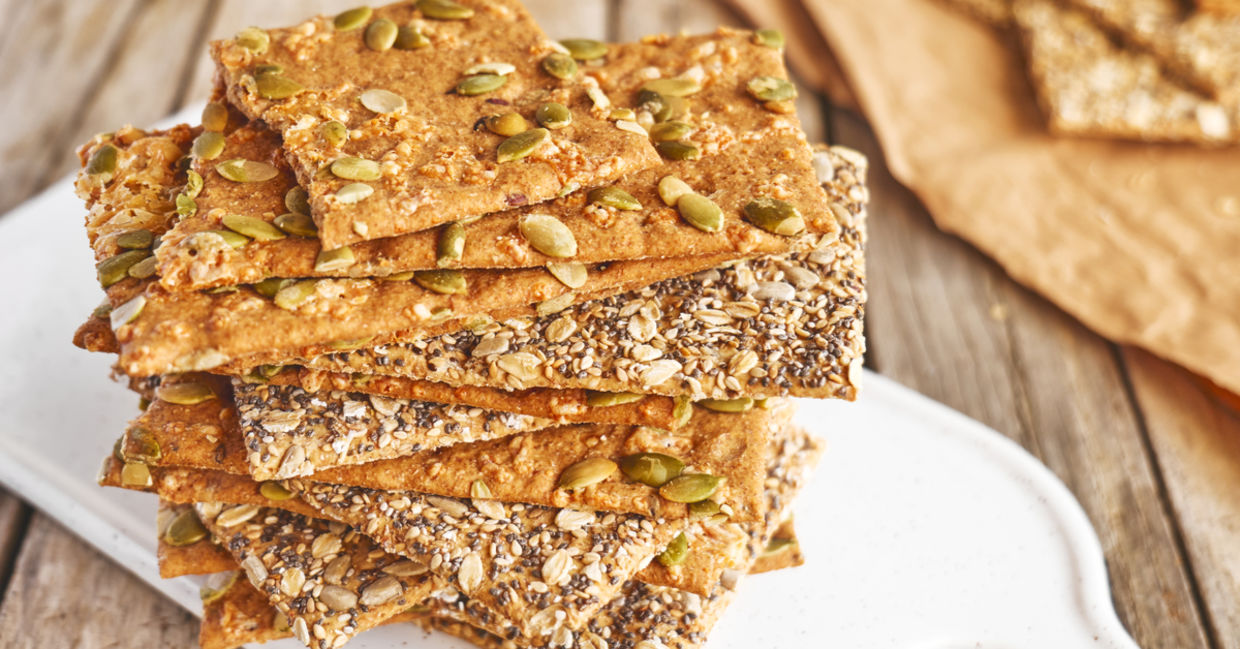 A selection of homemade seed crackers are displayed on a cutting board.