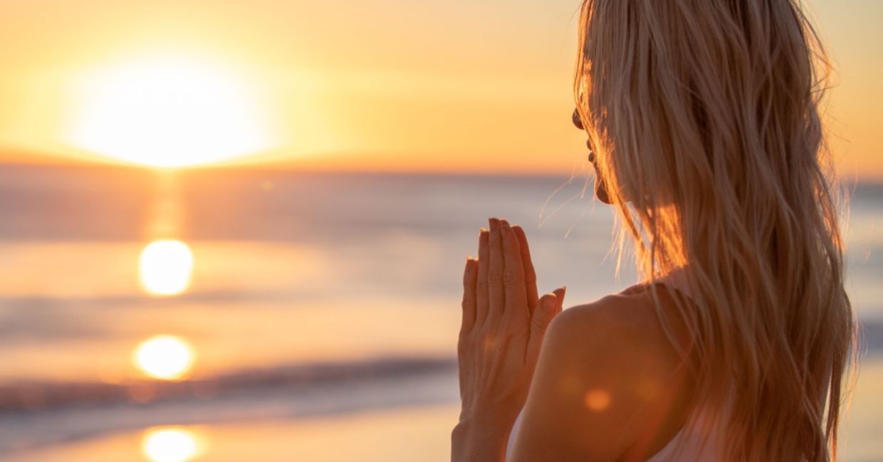 Girl meditating at sunset on beach