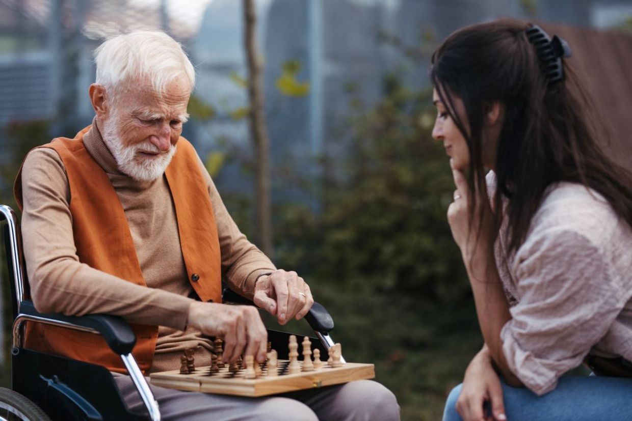 Patient young woman playing chess with a senior.