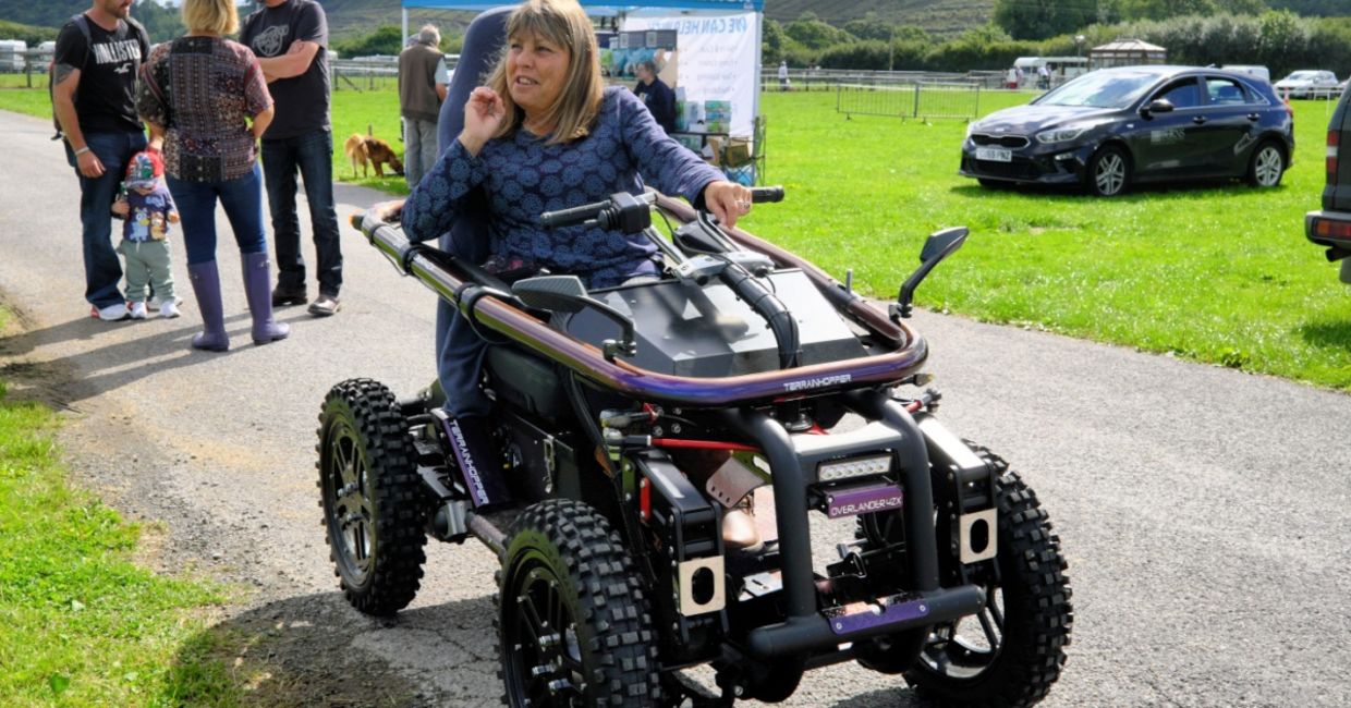 A woman using an all terrain motorized wheelchair.