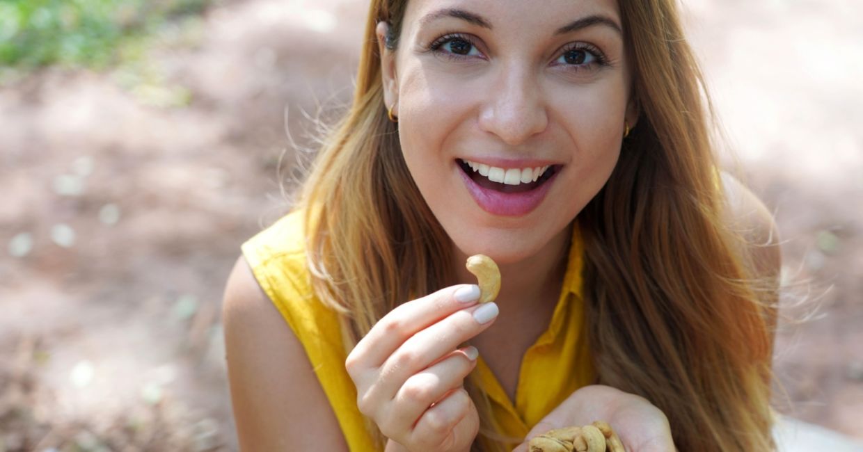 Young woman enjoying cashew nuts.