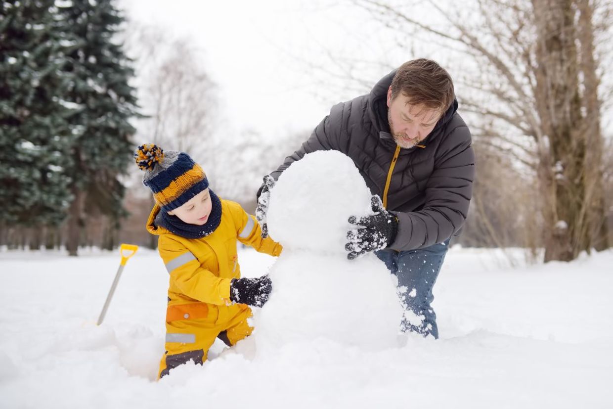 Father and son building a snowman.