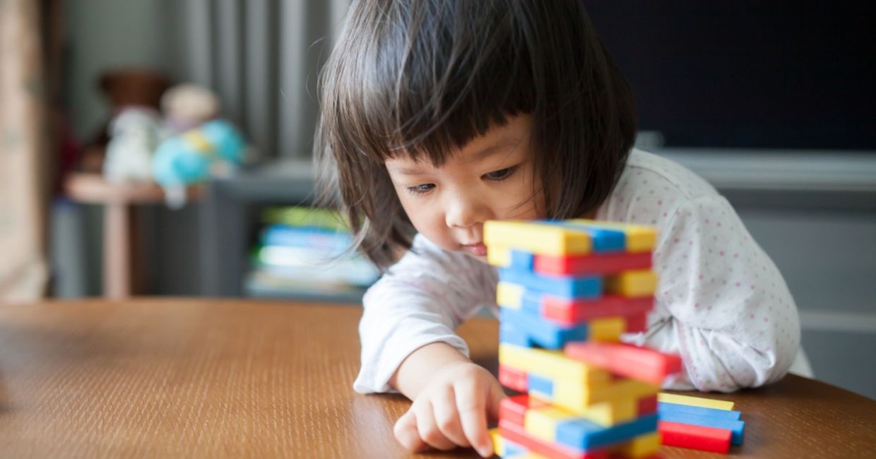 Little preschooler playing with wooden blocks.