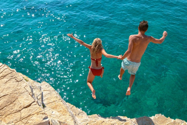 A couple jumps into the sea. 
